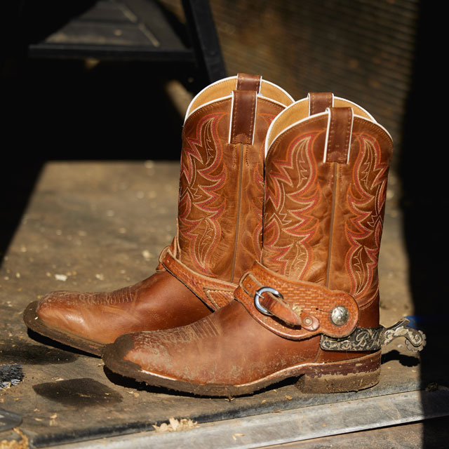 A close up photo of cowboy boots placed in a barn.